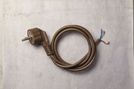 a used and broken power outlet with its wires neatly coiled lying on the floor