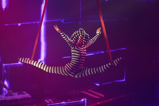 Flexible young woman make performance on aerial straps, flexible split on aerial straps, aerial circus show, purple white light. Flexible woman gymnas