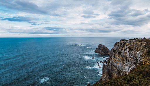 A high angle shot of the sea near the mountain under a cloudy sky in Cabo Penas, Asturias, Spain