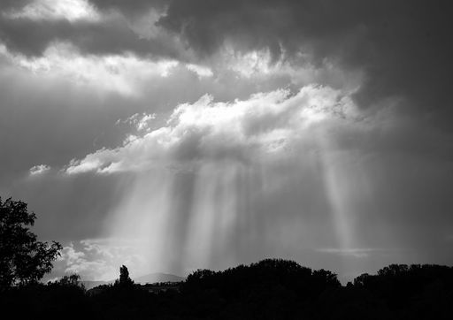 A beautiful shot of a landscape under the big white clouds in grayscale