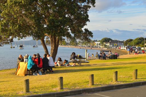 Group of people sitting around table for outdoor meal at Bucklands Beach