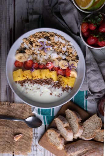 A vertical shot of healthy breakfast with oatmeal, pineapples, strawberries, bananas, bread, milk