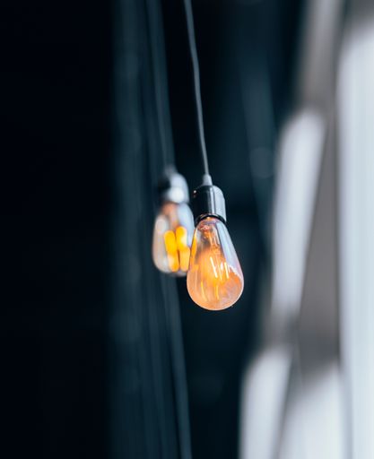 A selective focus of two light bulbs hanging on a ceiling against blue curtains