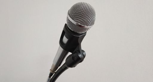 A microphone on a stand against a white wall background.
