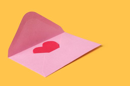 Minimal composition with a pink envelope with red heart inside for valentine day on yellow background. Copy space for text