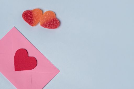 Minimal composition with a pink envelope with red heart inside, and a two sweet gummy hearts for valentine day. Copy space for tex
