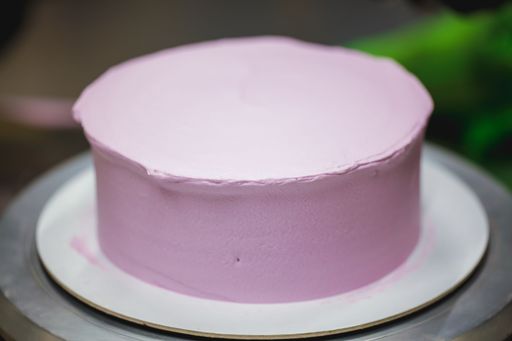 A closeup shot of a blank cake covered in baby pink frosting