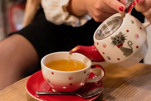 A closeup shot of a female pouring tea in a beautiful cup on an isolated background