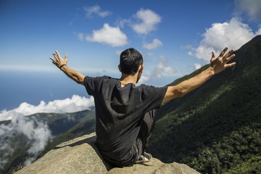 A back view of a hiker sitting on a rock on top of the Avila mountain, Caracas, Venezuela