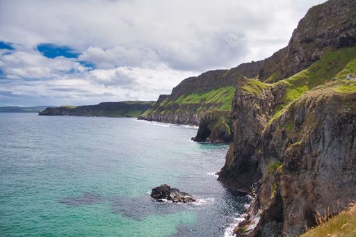 A beautiful view of a cliff and calm sea under the blue cloudy sky