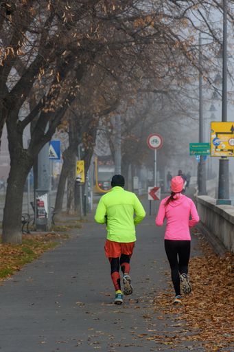 A vertical shot of a couple jogging on a misty morning in the city of Budapest, Hungary