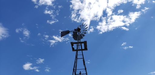 A low-angle shot of the metal pinwheel against a blue sky