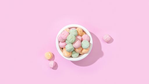 A top view of a bowl of jelly candies with different flavours isolated on a pastel pink background