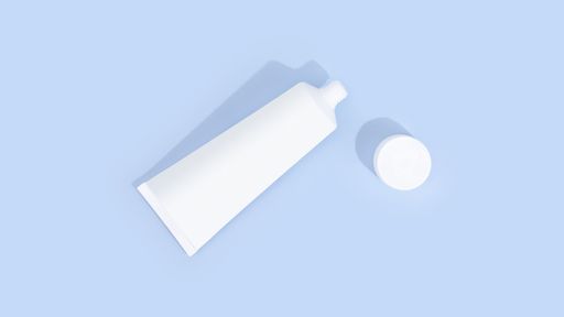 A white unbranded toothpaste tube isolated on a light blue background