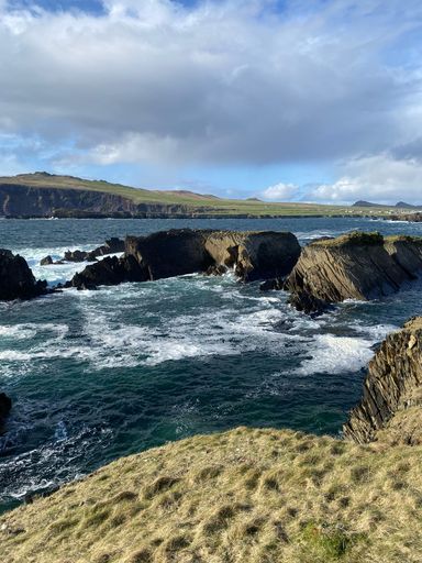 A vertical shot of a seascape with rock formations under a cloudy sky