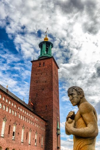 A vertical shot of Stockholm City Hall and a statue in front of it in Sweden
