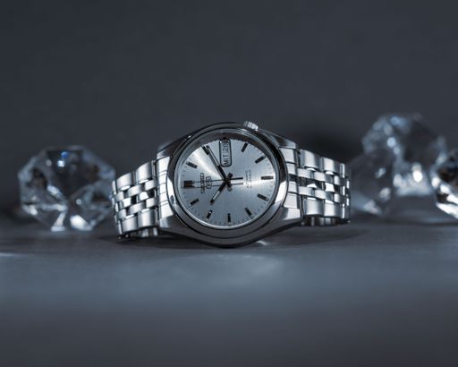 A close-up shot of a hand watch Seiko 5 with diamonds on a gray background