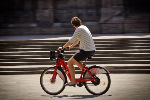 A young man riding an urban bicycle and passing quickly near the cathedral square of Barcelona, Spain