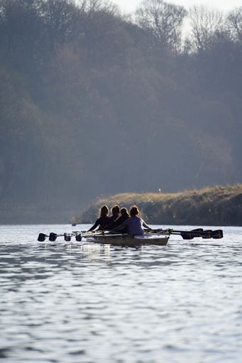 A vertical shot of girls sailing a small boat in the lake