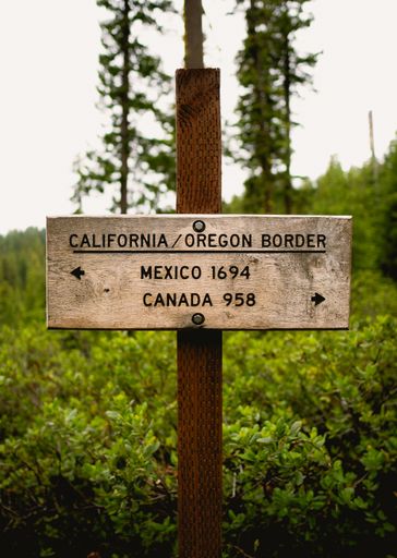 A vertical shot of the sign at the California-Oregon border and showing the distance to Mexico and Canada