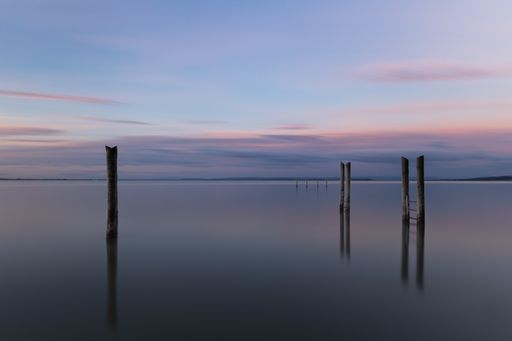 A wooden pier reflecting on the sea under the beautiful sunset sky