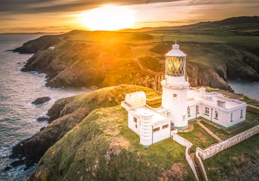 An aerial view of white lighthouse in UK during sunset