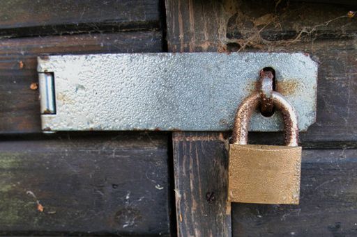 A closeup shot of a metal padlock on the old wooden door