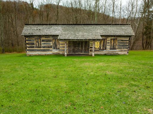 A scenic view of wooden rural cabins on a green lawn