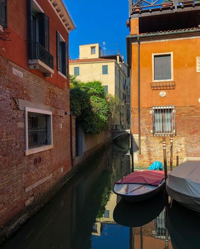 A vertical shot of canoes in front of the buildings on a sunny day in Venice, Italy
