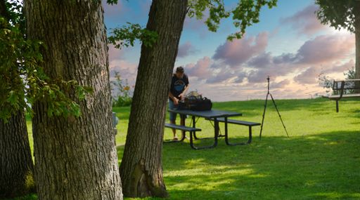 A photographer setting up his equipment in the field under a blue sky