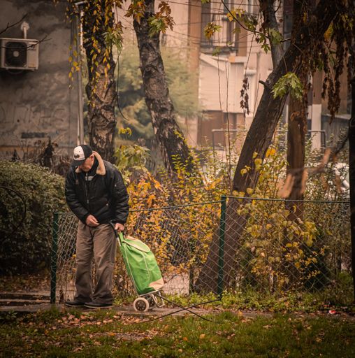 A senior man carrying his bag on wheels in a park