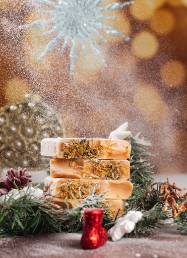 A set of handmade Christmas-themed soaps featuring a snowflake pattern in the background