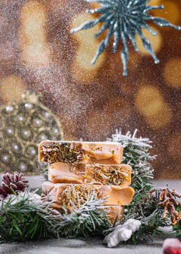 A set of handmade Christmas-themed soaps featuring a snowflake pattern in the background