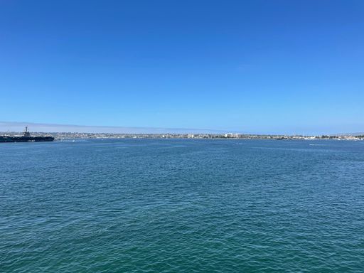 A large ship is navigating through a picturesque bay