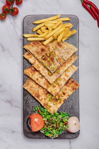 A plate full of delicious french fries, accompanied by a selection of other food items, including tomatoes