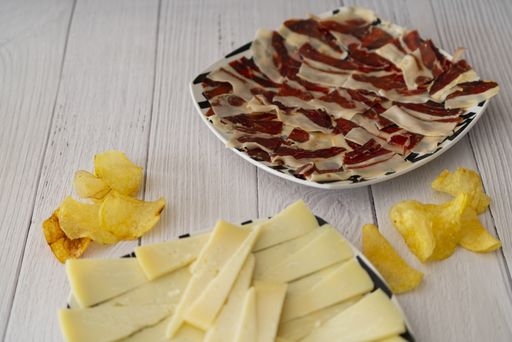 A high angle shot of bacon, cheese, and chips on a table