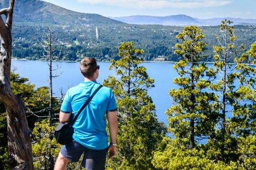 A young Caucasian male admiring the beautiful view of a lake from the mountain peak