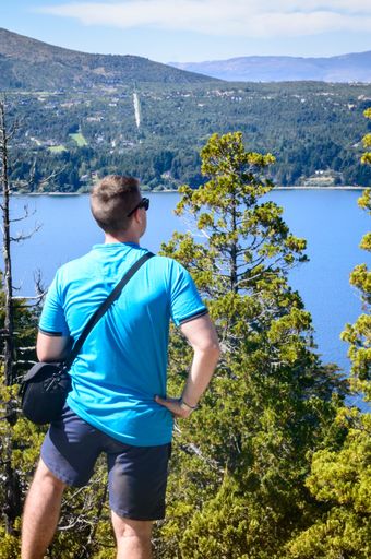 A young Caucasian male admiring the beautiful view of a lake from the mountain peak
