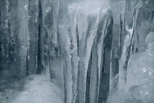 A scenic, tranquil forest landscape featuring intricate ice sculptures perched atop the rocks of a babbling stream
