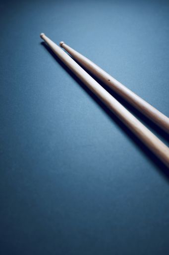 A vertical high angle shot of two drumsticks on a blue surface