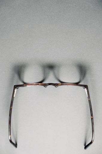 A vertical high angle shot of an old brown glasses on a grey surface