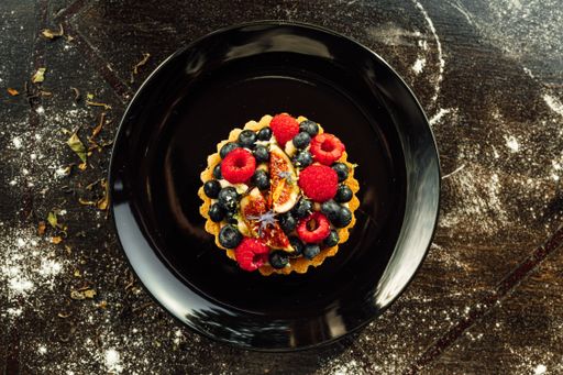 A closeup of a tart with strawberries and blueberries on top