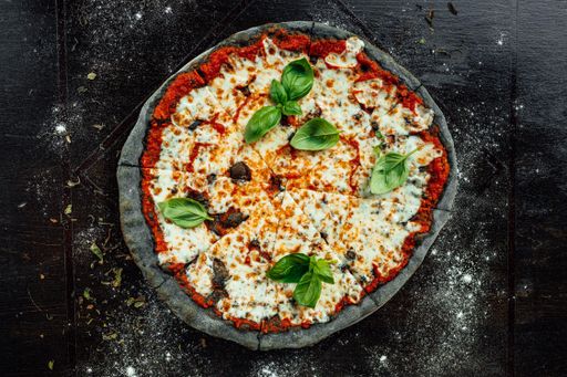 A top view of appetizing pizza with black dough