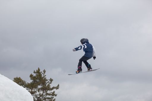 A snowboarder jumping high through the air at the Wisp Ski Resort in Deep Creek Lake Maryland