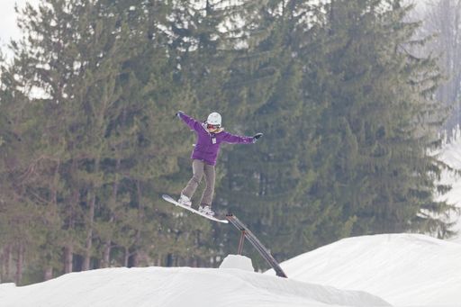 A snowboarder jumping high through the air at the Wisp Ski Resort in Deep Creek Lake Maryland