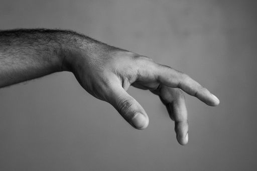 A greyscale shot of a males hand showing a gesture