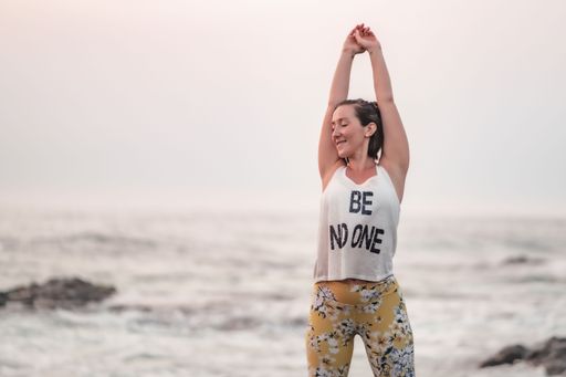 A Caucasian woman stretching out on the beach, doing fitness