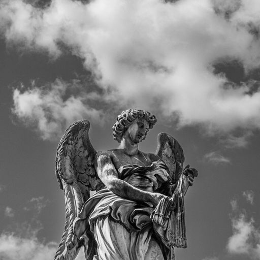 A grayscale of an angel statue against the daytime sky and clouds