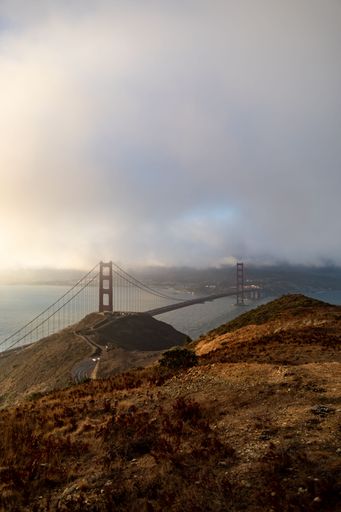 A vertical shot of the Golden Gate bridge under a cloudy sky in San Francisco, California