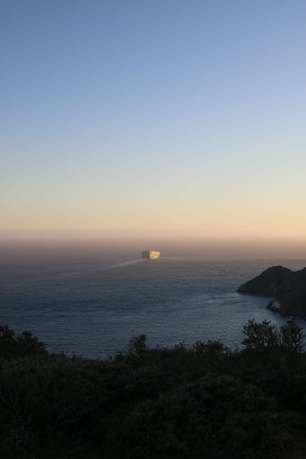 A cargo ship sailing into the distance at sunset. San Francisco, California.